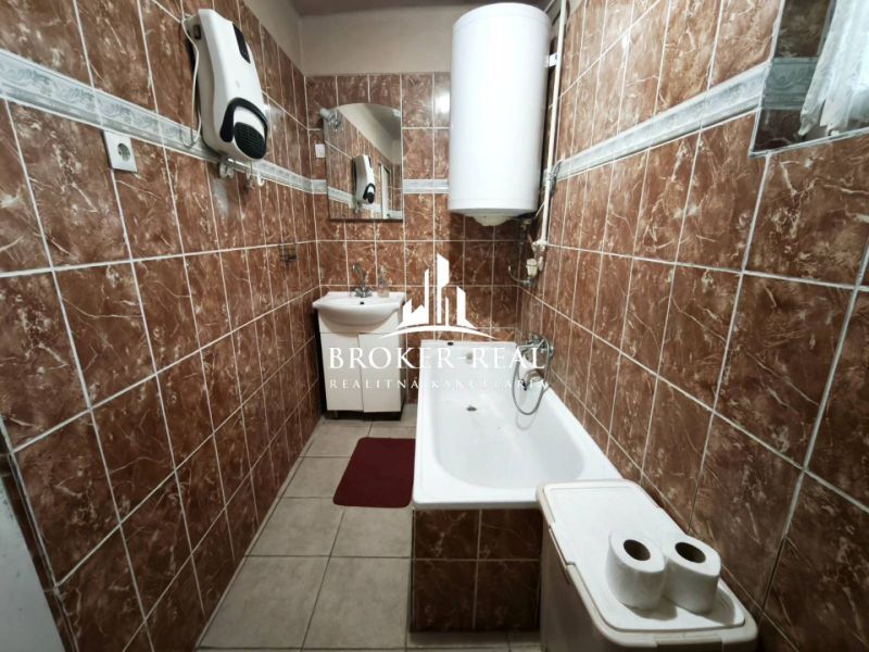 Ein Badezimmer in einem Einfamilienhaus mit braunen Fliesen und einer Badewanne.