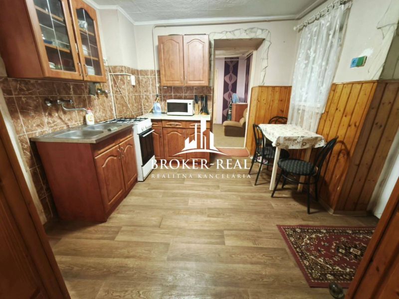 Küche in einem Einfamilienhaus mit Holzdekor, Schränken und Essecke.