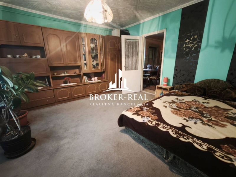 Ein Zimmer in einem Einfamilienhaus mit Holzmöbeln, grünen Wänden und einem bequemen Bett.
