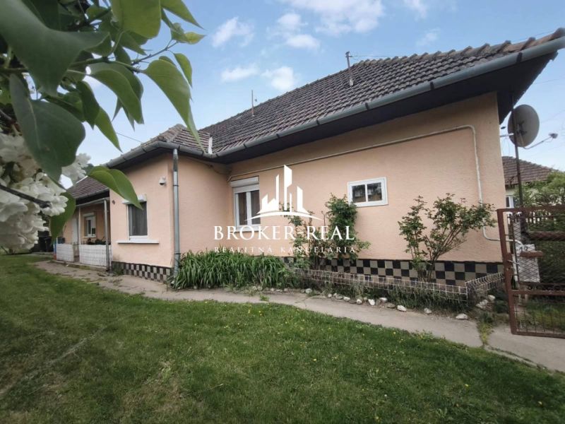 Ein Einfamilienhaus in Bódvaszilas mit hellen Wänden, einem schrägen Dach und einem grünen Rasen.