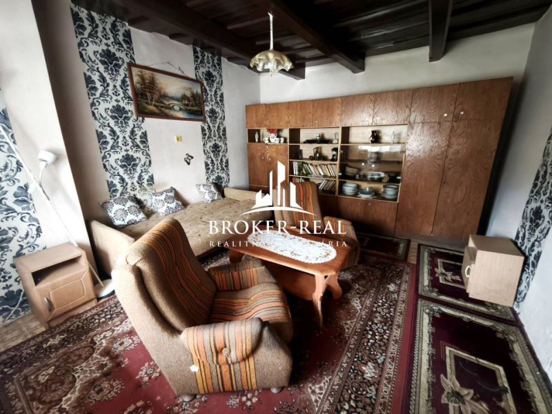 Wohnzimmer in einem Einfamilienhaus mit Teppichen und einer Wohnwand aus Holz.