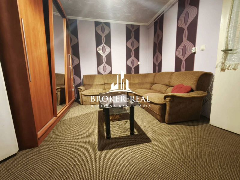 Wohnzimmer in einem Einfamilienhaus mit gestreiftem Sofa und bunter Tapete.
