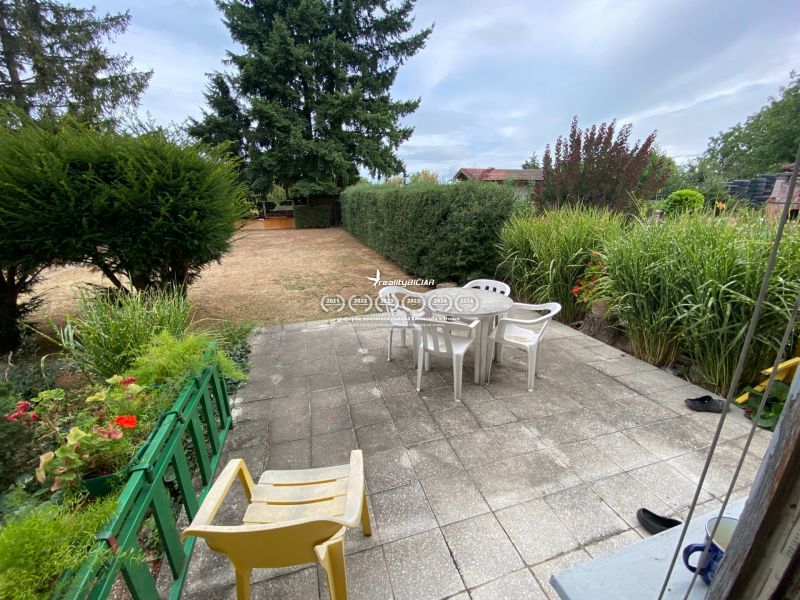 Der Garten eines Einfamilienhauses in Zvončín mit einer befestigten Terrasse, Stühlen und grünen Pflanzen.
