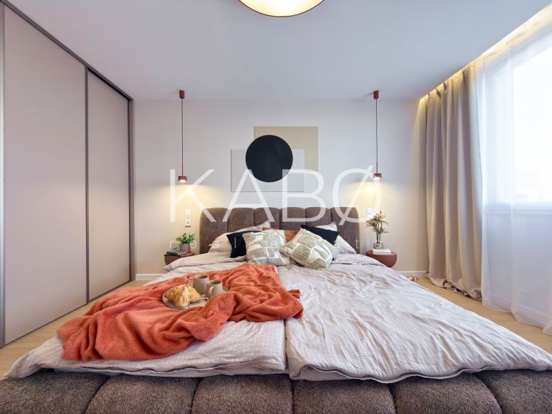 Schlafzimmer in einer 3-Zimmer-Wohnung mit Bett, Vorhängen und Schrank; Boden mit Holzdekor.