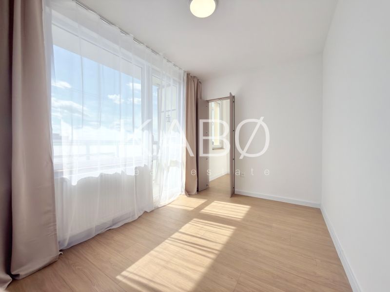 Ein helles Zimmer mit Vorhängen und einem Boden in Holzoptik in einer 3-Zimmer-Wohnung.