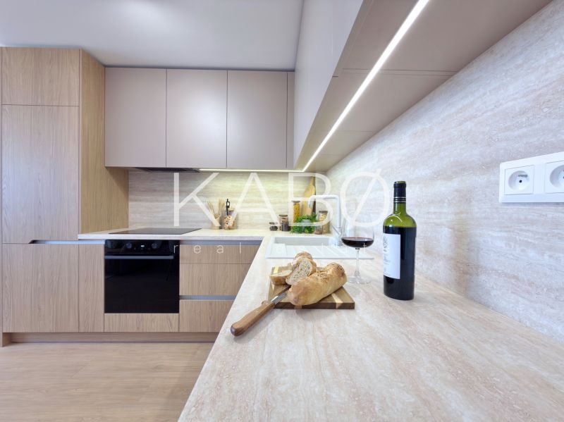 Küche in einer 3-Zimmer-Wohnung mit Wein, Brot und einem Boden in Holzoptik.