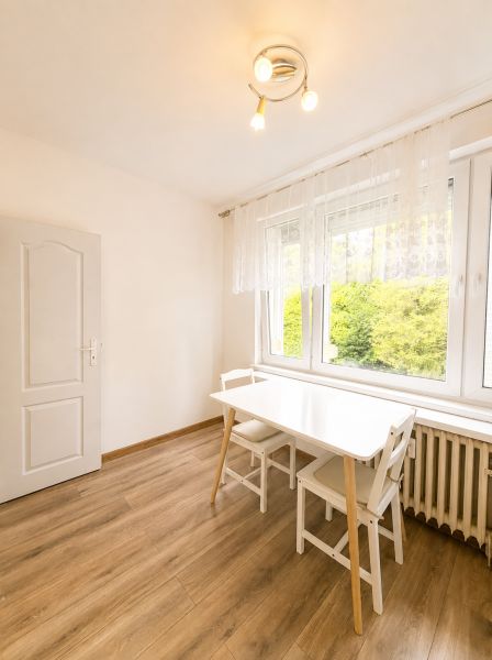 Essbereich mit weißem Tisch und Stühlen, Boden mit Holzdekor, 3-Zimmer-Wohnung.