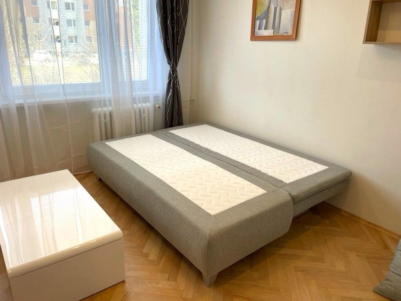 Einzimmerwohnung mit Bett, Holzboden und weißem Tisch.
