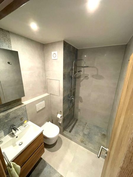 Kompaktes Badezimmer in einem Studio-Apartment mit offener Dusche und Fliesen.