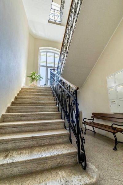 Eine Treppe mit einem Metallgeländer und einer Bank in einem Büro, beleuchtet durch ein großes Bogenfenster.