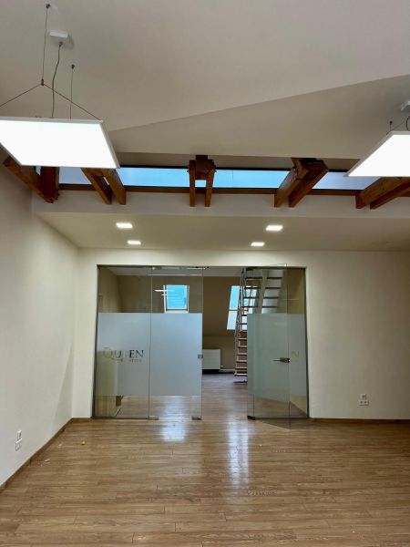 Innenraum eines Büros mit Holzboden und Glastüren.