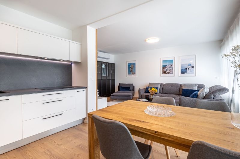 Küche und Wohnzimmer in einem Einfamilienhaus mit einer Arbeitsplatte aus Verbundwerkstoff und einem Boden mit Holzdekor.