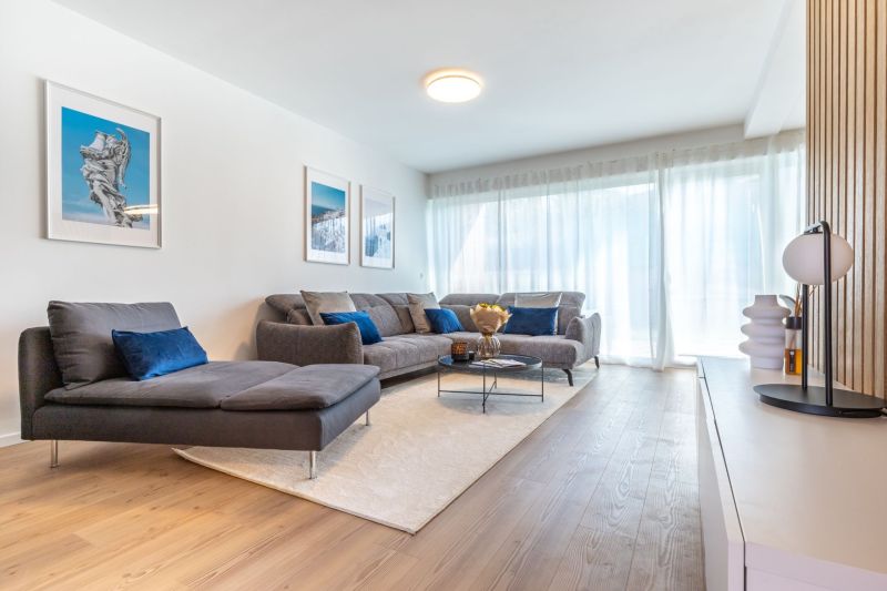 Wohnzimmer in einem Einfamilienhaus mit Sofa, Bildern und Boden mit Holzdekor.