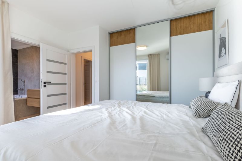 Ein Schlafzimmer in einem Einfamilienhaus mit einem großen Einbauschrank und einem Bett in hellen Farben.