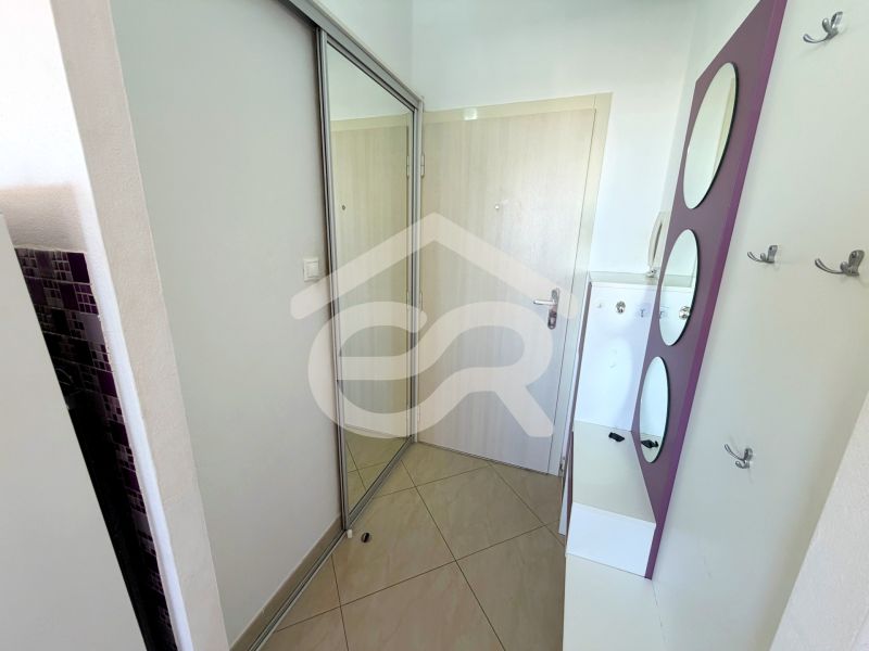 Eingangsflur in einer Einzimmerwohnung mit Fliesenboden und Spiegelschrank.