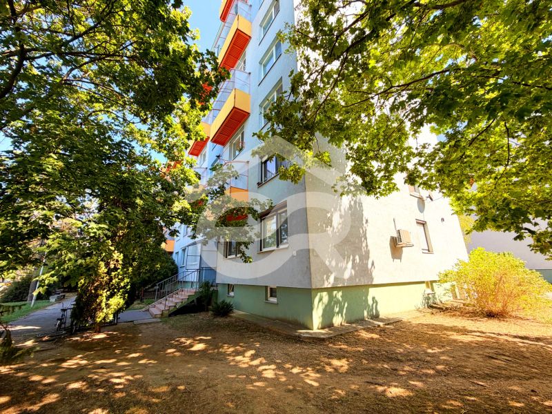 Ein Wohnblock mit bunten Balkonen in der Straße Lúky in Vráble, umgeben von Bäumen.