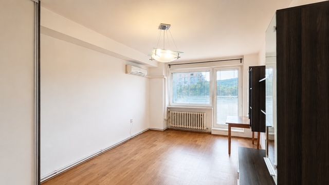Wohnzimmer mit Holzboden, Klimaanlage und großem Fenster in einer 3-Zimmer-Wohnung.