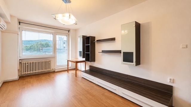Ein Zimmer in einer 3-Zimmer-Wohnung mit einem Boden in Holzoptik und eingebauten Regalen.