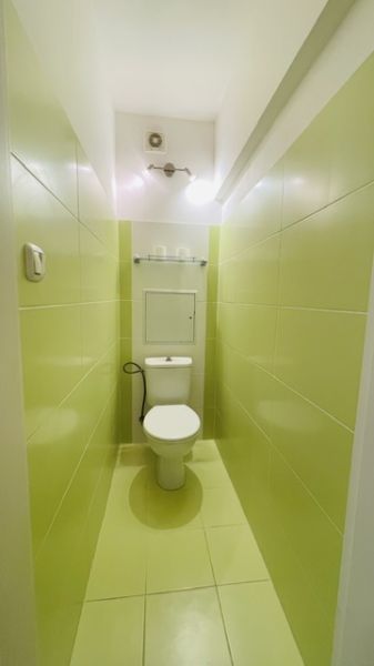 Ein schmales Badezimmer mit hellgrünen Fliesen und einer Toilette in einer 3-Zimmer-Wohnung.