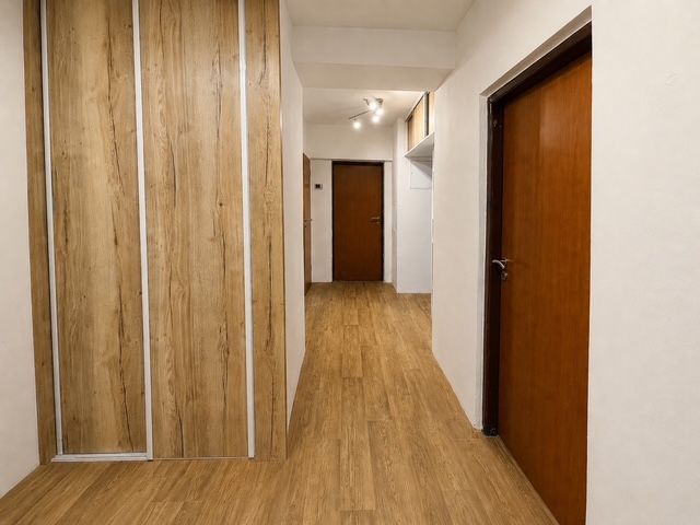 Der Flur in einer 3-Zimmer-Wohnung mit einem Boden in Holzoptik und eingebauten Schränken.