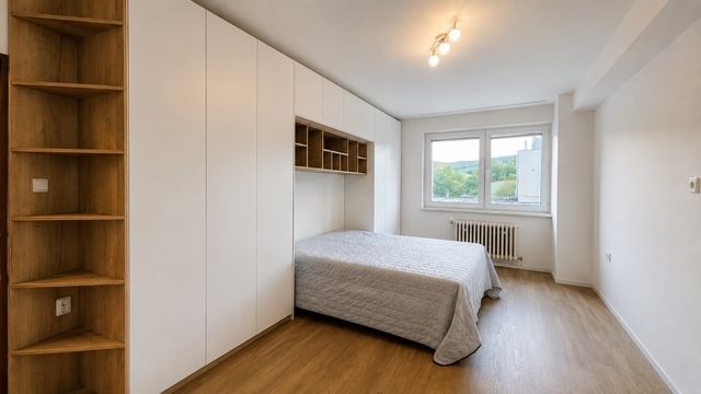 Schlafzimmer in einer 3-Zimmer-Wohnung mit Bett, Einbauschränken und Boden in Holzoptik.