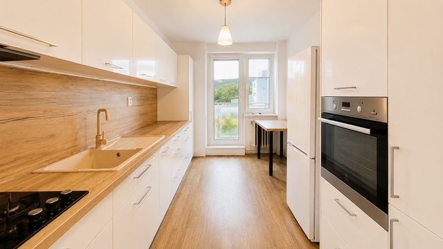 Eine Küche in einer 3-Zimmer-Wohnung mit einem Boden in Holzoptik, einer weißen Küchenzeile und einem Ofen.