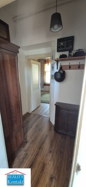 Ein schmaler Flur in einer 2-Zimmer-Wohnung mit einem Holzboden und einem Schrank.