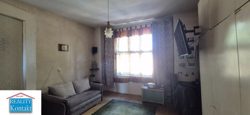 Wohnzimmer in einer 2-Zimmer-Wohnung mit Sofa, Fernseher und Holzboden.