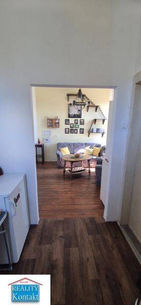 Innenraum einer 2-Zimmer-Wohnung mit Holzboden und bequemen Sitzgelegenheiten.