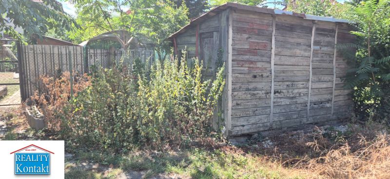 Ein Holzunterstand, umgeben von Vegetation, im Hof an der Straße Za 3 mostami in Nové Zámky.
