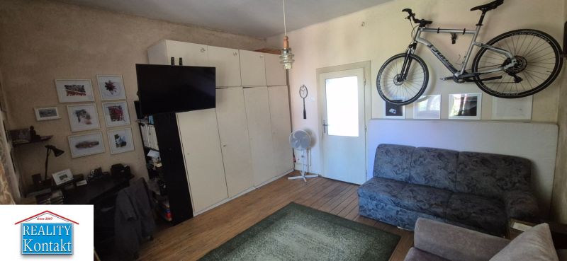 Wohnzimmer einer 2-Zimmer-Wohnung mit Sofa, Fernseher und Fahrrad an der Wand.