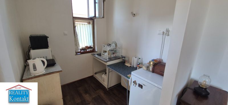 Küche in einer 2-Zimmer-Wohnung mit Geräten und Boden in Holzoptik.