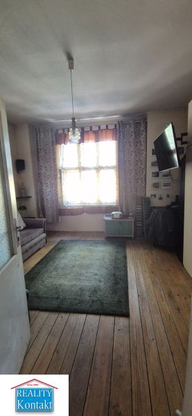 Ein Zimmer in einer 2-Zimmer-Wohnung mit einem Holzboden und einem Fernseher an der Wand.