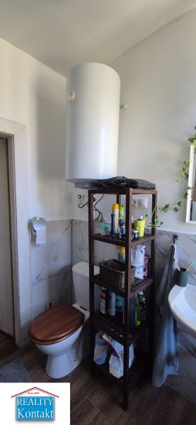 Das Badezimmer in der 2-Zimmer-Wohnung enthält eine Toilette, ein Regal und ein Waschbecken.