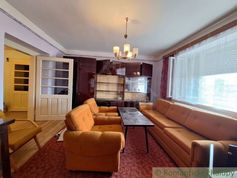 Wohnzimmer in einem Einfamilienhaus mit orangefarbenen Möbeln und einer Vitrine.