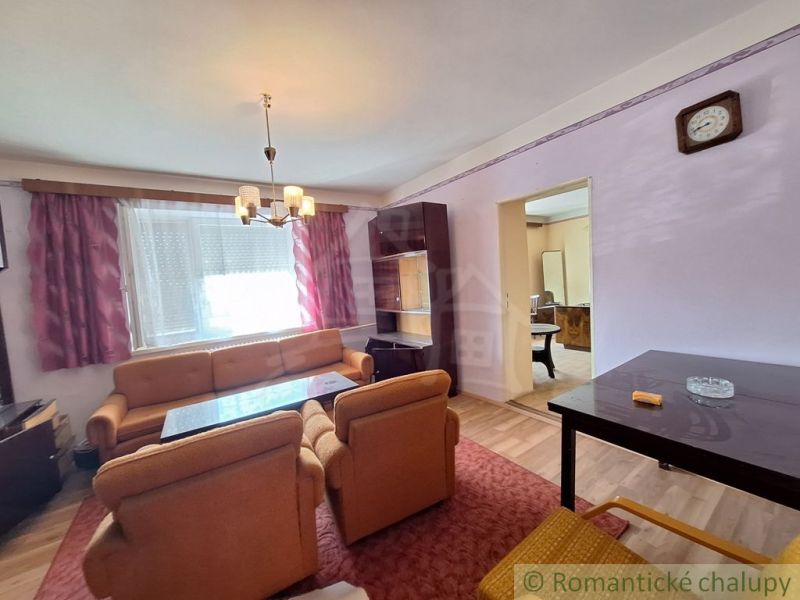 Wohnzimmer eines Einfamilienhauses mit einer orangefarbenen Sitzgarnitur und einer Schrankwand.
