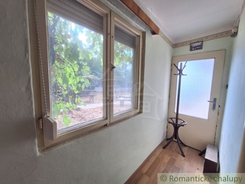 Ein enger Flur in einem Einfamilienhaus mit einem Fenster, einem Kleiderhaken und einem Boden mit Holzdekor.