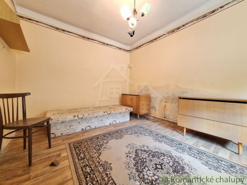 Ein Zimmer mit einem Bett, einem Stuhl und Teppichen, einem Boden mit Holzdekor, Eckmöbel.
