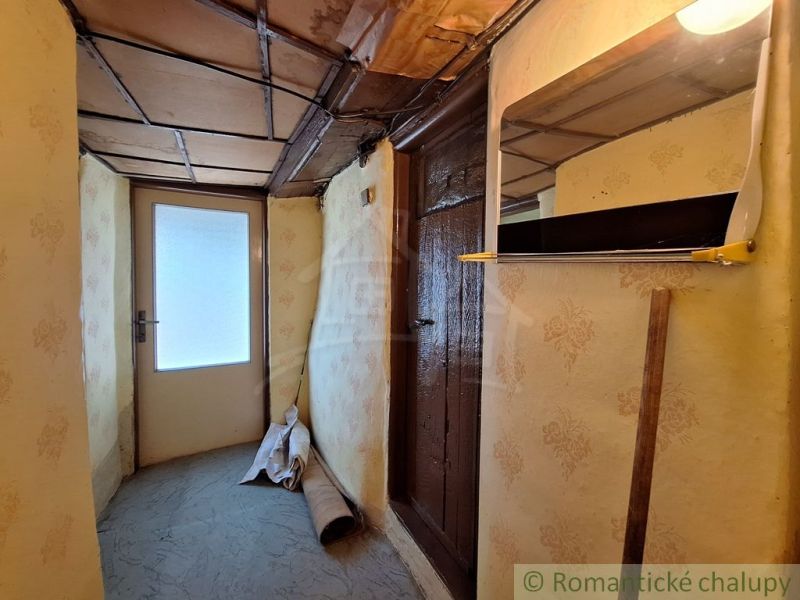 Ein Flur in einem Landhaus mit einer Holzdecke und dekorativer Tapete an den Wänden.