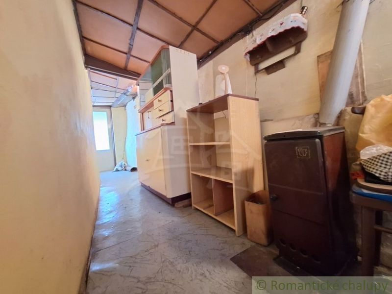 Ein enger Flur in einem Einfamilienhaus mit Gasofen, Regalen und einem Schrank.