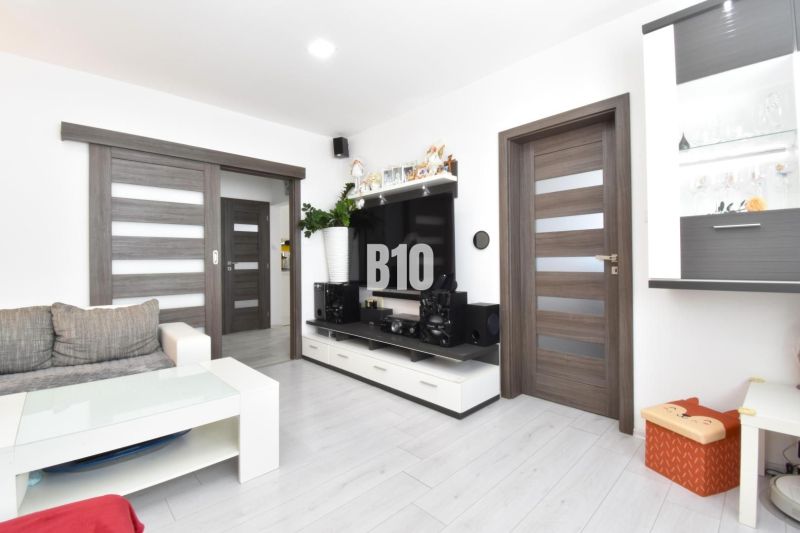 Wohnzimmer in einer 3-Zimmer-Wohnung mit Holzboden und weißen Möbeln.