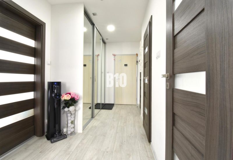 Flur mit einem Spiegelschrank und einem Boden in Holzoptik in einer 3-Zimmer-Wohnung.