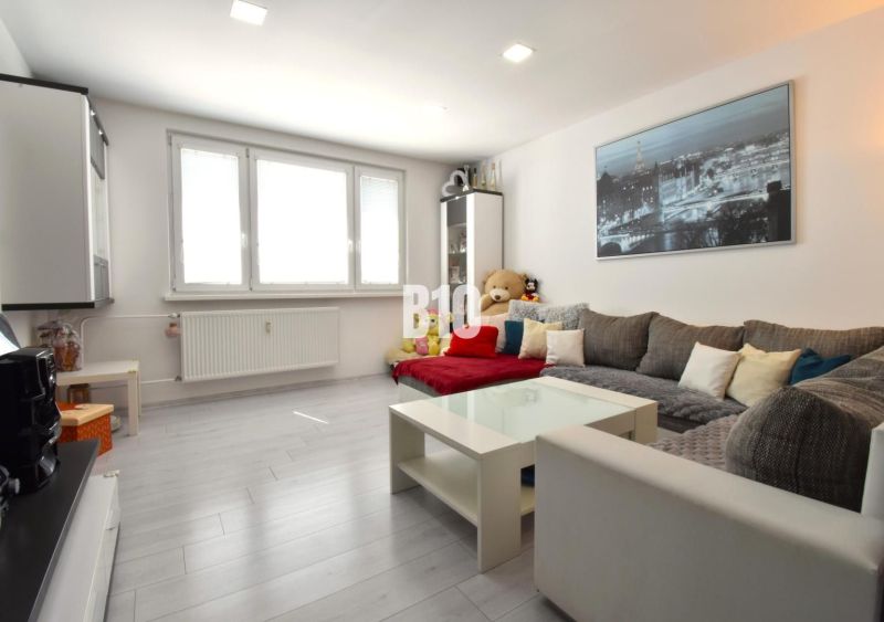 Wohnzimmer in einer 3-Zimmer-Wohnung mit Holzboden und großem Sofa.