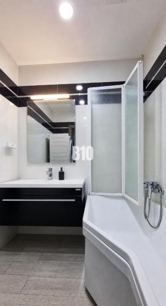 Ein Badezimmer in einer 3-Zimmer-Wohnung mit einer Badewanne, einem Waschbecken und einem Boden in Holzoptik.