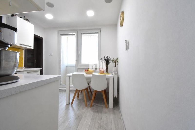 Essbereich mit Tisch und Stühlen auf einem Boden mit Holzdekor in einer 3-Zimmer-Wohnung.