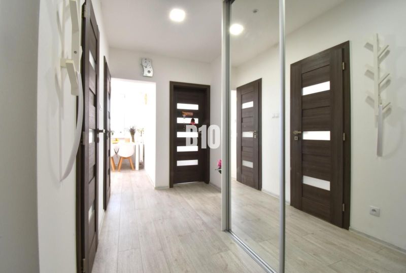 Flur in einer 3-Zimmer-Wohnung mit einem Spiegelschrank und einem Boden in Holzoptik.