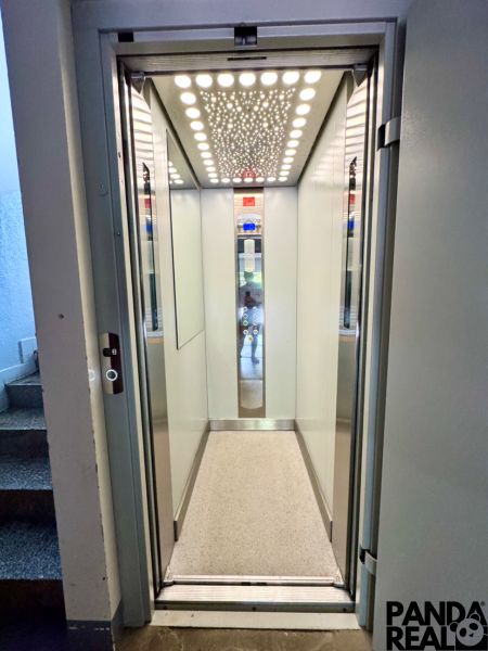 Aufzug mit beleuchteter Decke und hellen Wänden in einem Wohnhaus.