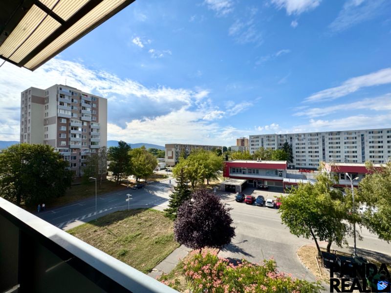 Blick aus einer Einzimmerwohnung in Topoľčany auf die Siedlung mit Grünflächen und einem Auto.