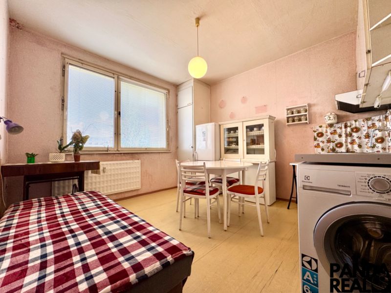 Küche in einer Einzimmerwohnung mit Tisch, Stühlen, Kühlschrank und dekorativen Elementen.