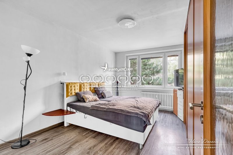 Schlafzimmer mit Bett und Holzboden in einer Zweizimmerwohnung.